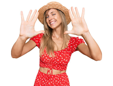 Beautiful caucasian woman wearing summer hat showing and pointing up with fingers number ten while smiling confident and happy.