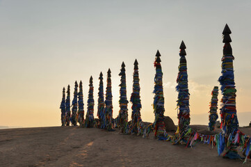 Shamanic pillars with colored ribbons on Olkhon Island near Lake Baikal. Ritual pillar. Sunset view.