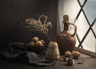 Modern still life with walnuts and a clay jug near the window