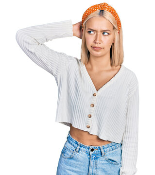 Beautiful young blonde woman wearing casual white sweater confuse and wondering about question. uncertain with doubt, thinking with hand on head. pensive concept.