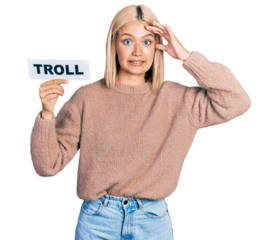 Beautiful young blonde woman holding troll banner stressed and frustrated with hand on head, surprised and angry face