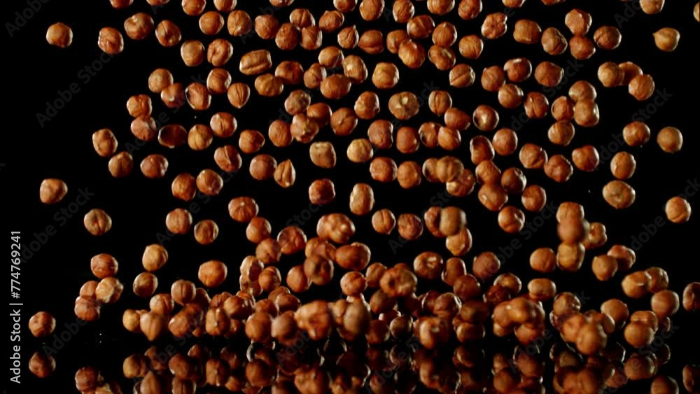 Poster super slow motion of falling hazelnuts with reflection. isolated on black background. filmed on high