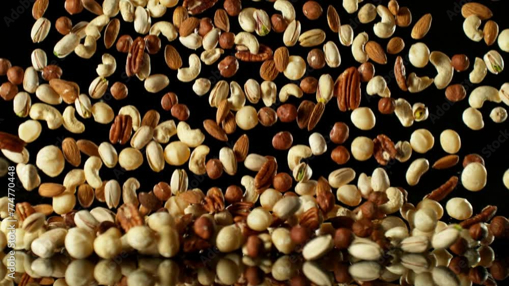 Poster super slow motion of falling mix nuts with reflection. isolated on black background. filmed on high 
