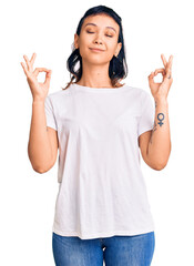 Young woman wearing casual clothes relax and smiling with eyes closed doing meditation gesture with fingers. yoga concept.