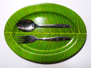 Empty green plate leaf pattern theme with spoon and fork isolated white background