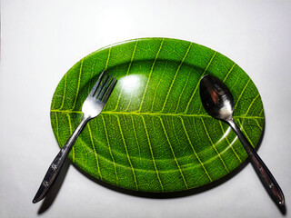 Empty green plate leaf pattern theme with spoon and fork isolated white background