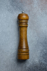 Top view close up wooden pepper mill on concrete gray background.