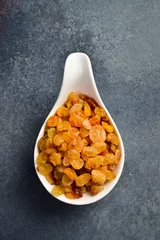 Foto op Plexiglas Close up of dried raisins in a ceramic bowl. On a dark concrete background. © Yaruniv-Studio