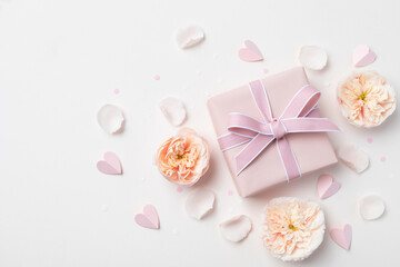 Birthday, Woman or Mothers Day greeting card. Pink hearts, rose flowers and gift box on pastel table top view. Flat lay.