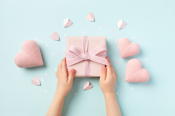 Child hands holding a gift or present box decorated with pink hearts for Happy mothers day. Holiday greting card. - 774782836
