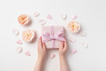 Child hands holding a gift or present box decorated with flowers and hearts for Happy mothers day. Holiday concept top view. - 774782889