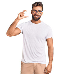 Young hispanic man wearing casual clothes and glasses smiling and confident gesturing with hand...