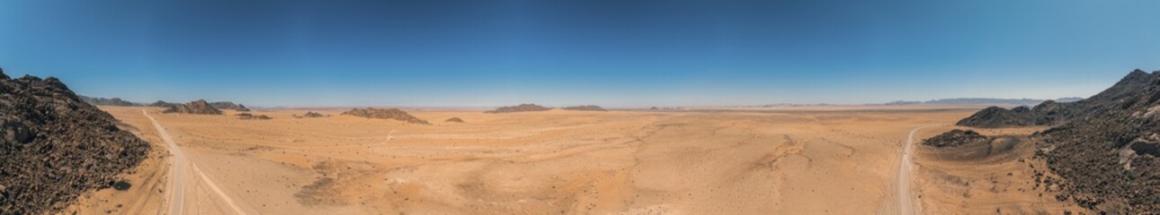 Panoramic drone picture of a lonely gravel road through the desert