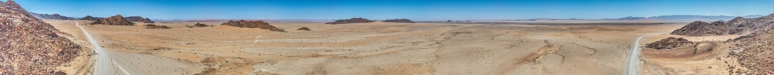 Panoramic drone picture of a lonely gravel road through the desert