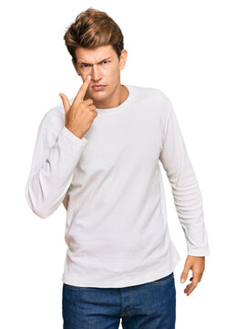 Handsome caucasian man wearing casual white sweater pointing to the eye watching you gesture, suspicious expression