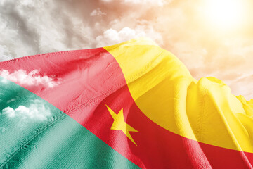 Cameroon national flag cloth fabric waving on beautiful cloudy Background.