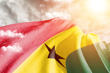 Ghana national flag cloth fabric waving on beautiful cloudy Background.