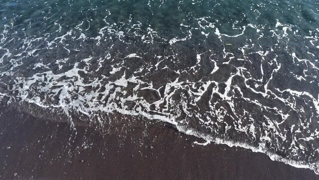 Wellen am schwarzen Strand von Amed, Karangasem, Bali, Indonesien