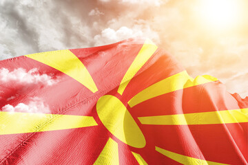 North Macedonia national flag cloth fabric waving on beautiful cloudy Background.