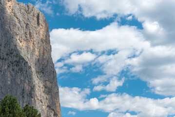 Vertical rock wall in the famous Dolomites mountain chain, Italy, good for free climbers. Blue sky with white clouds on the right, with copy-space.