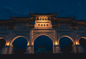 Obraz premium Main gate at Chiang Kai-shek Mausoleum Memorial Monument at night in Freedom Square, Taipei, Taiwan. Panoramic view of Memorial Hall Square. National monument. Dark sky with clouds in a dark blue sky