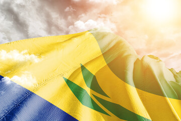 Saint Vincent and the Grenadines national flag cloth fabric waving on beautiful cloudy Background.