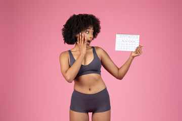 Stressed black woman holding a period calendar