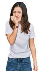 Fototapeta premium Young beautiful woman wearing casual white t shirt looking stressed and nervous with hands on mouth biting nails. anxiety problem.