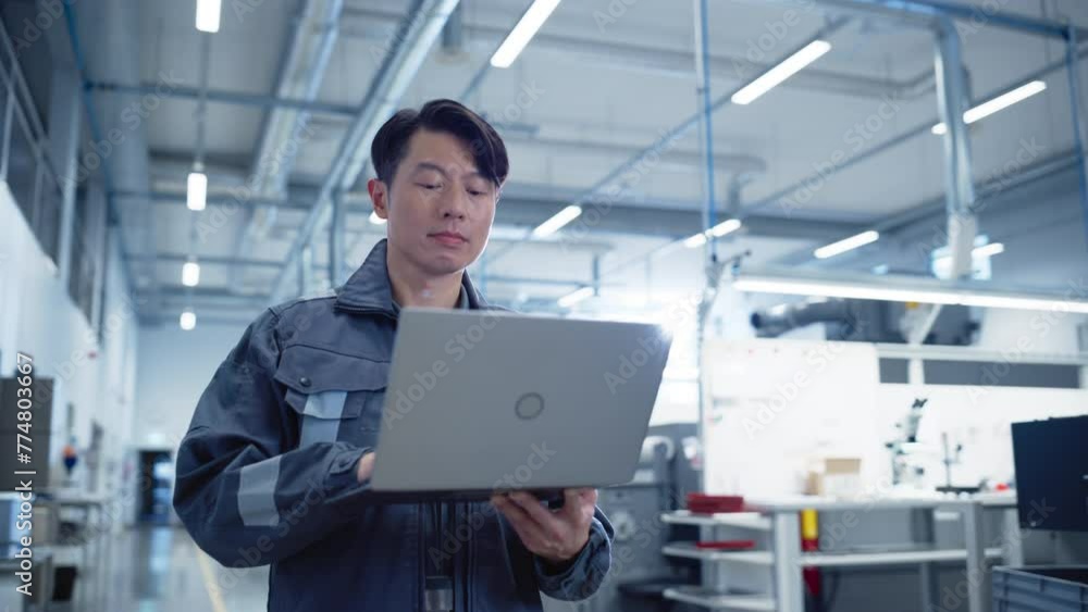 Leinwandbilder portrait of an asian industrial specialist standing in electronics manufacturing facility and using 