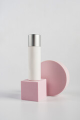 Plastic white tube for cream or lotion. Skin care or sunscreen cosmetic with stylish props on white background.