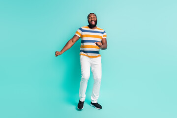 Full length photo of cool cheerful man wear striped t-shirt having fun isolated turquoise color background