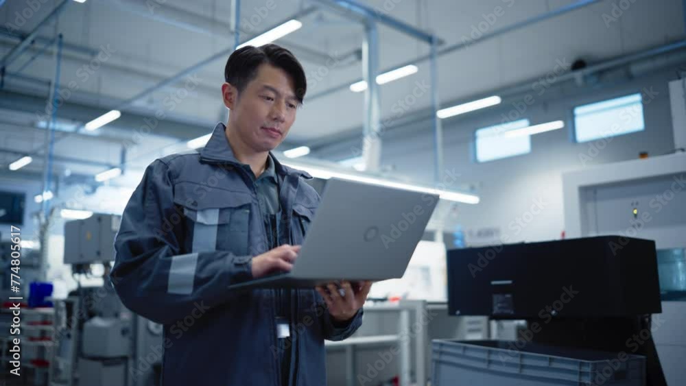 Poster Portrait of a Precision Mechanics Technician Working on a Laptop Computer at a Factory Space. Asian Specialist Developing, Maintaining, Calibrating Software for Machine Parts Production and Assembly