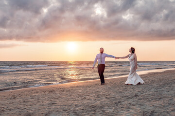 Couple walking along a beach at sunset.