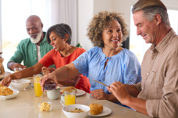Group Of Smiling Mature Friends On Vacation Or At Home Eating Breakfast Together