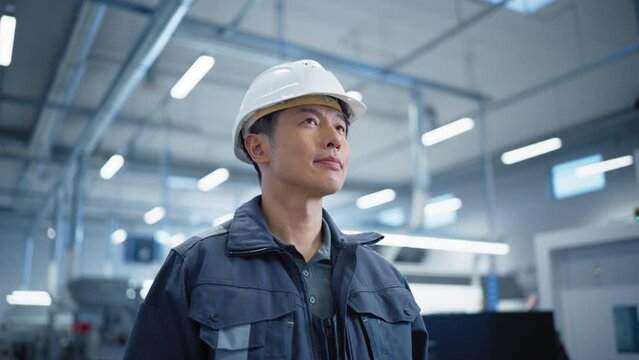 Portrait of an Asian Engineer Standing in a Factory, Looking Around the Facility. Industrial Specialist Working at an Autonomous Electronics Manufacture, Producing Modern Computer Components