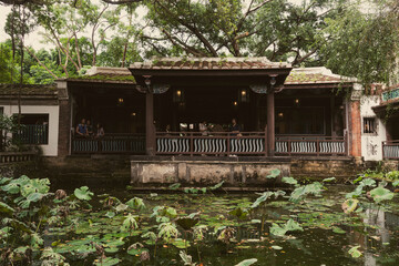 Historic Chinese style building in Asia. Ancient historic wooden mansion with pond and water lilies in the center of the Asian capital Taipei. Old historic house with pond and park in Taipei Taiwan.