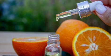 bottle of aromatic essence and fresh orange on the background of nature.