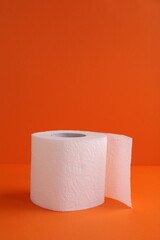 Soft toilet paper roll on orange background. Space for text