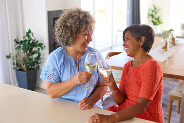 Two Mature Female Friends At Home Relaxing And Celebrating With Cheers Drinking Wine And Talking