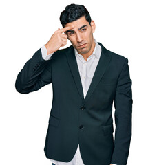 Handsome hispanic man wearing business clothes pointing unhappy to pimple on forehead, ugly infection of blackhead. acne and skin problem