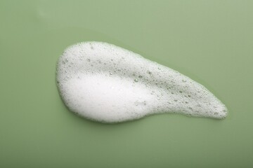 Sample of fluffy foam on green background, top view