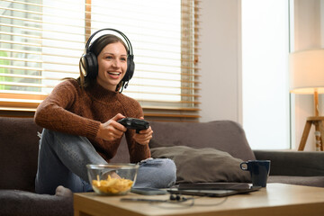 Overjoyed young woman wearing headset playing video game with joystick in at home