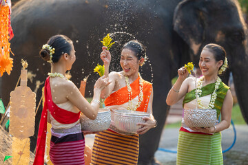 Songkran festival. Northern Thai people in Traditional clothes dressing splashing water together in...
