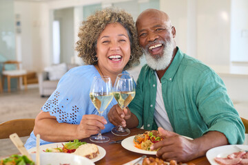 Portrait Of Loving Mature Couple At Home Enjoying Lunch With Wine Together