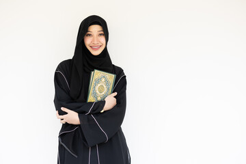 Portrait happy Saudi muslim niqab arab woman black chador with The Holy Al Quran book isolated on white. book cover arabic calligraphy translated to Al Quran