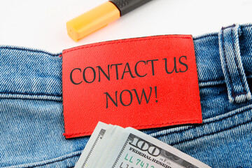 CONTACT US NOW word inscription on the leather insert of jeans with dollar bills sticking out