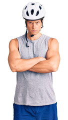 Young handsome man wearing bike helmet skeptic and nervous, disapproving expression on face with crossed arms. negative person.