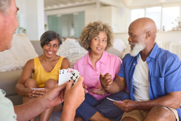 Group Of Mature Friends At Home Having Fun Playing Cards Together