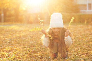 Happy girl playing with autumn leaves. Happy child walking and having fun in fall backyard.