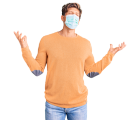 Young handsome man wearing medical mask crazy and mad shouting and yelling with aggressive expression and arms raised. frustration concept.